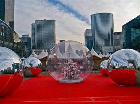 Two Snow Globes Sitting On Top Of A Red Carpet With Buildings In The