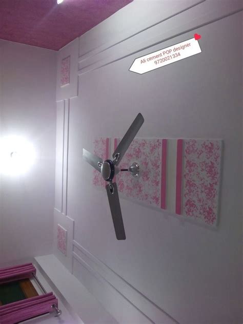 A Ceiling Fan Mounted To The Side Of A Wall With Pink And White Designs