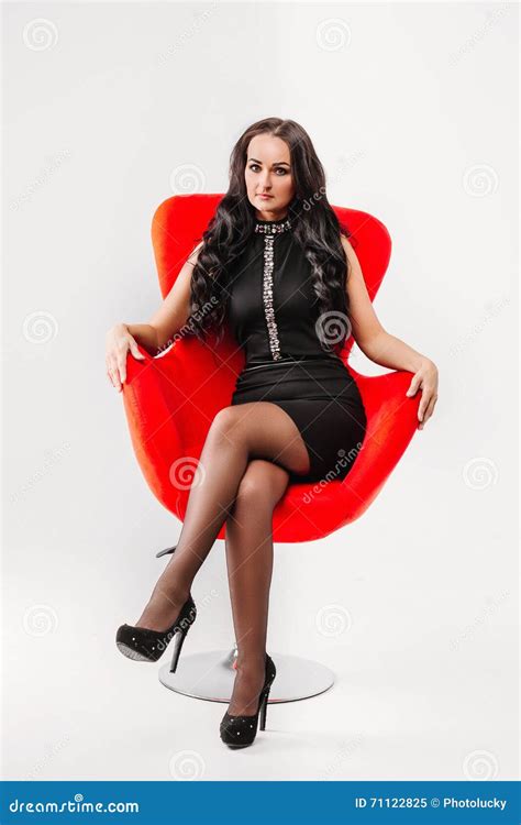 Beautiful Young Brunette Woman With Long Hair In A Black Dress Sitting