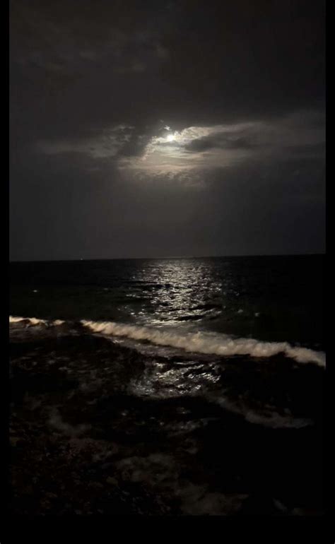 The Moon Is Shining Over The Ocean On A Dark Night With Waves Crashing