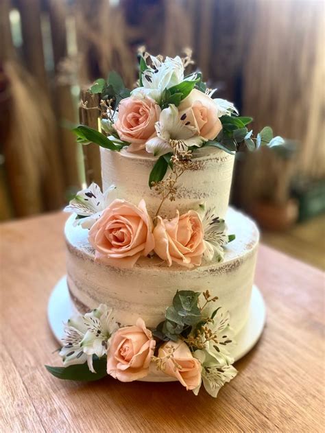 A Three Tiered Wedding Cake With Flowers On The Top And Bottom Sitting