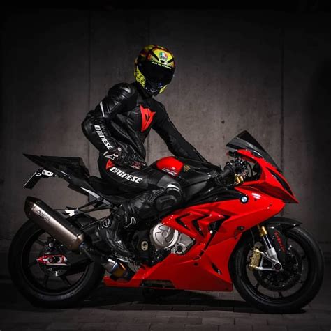 A Man Sitting On Top Of A Red Motorcycle Wearing A Helmet And Black