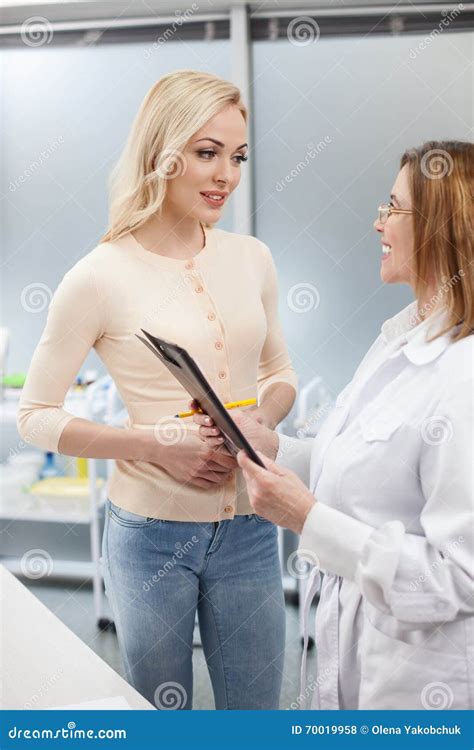 Gynecologist Asking Female Patient To Sit On Gynecological Chair For Examination Stock Image