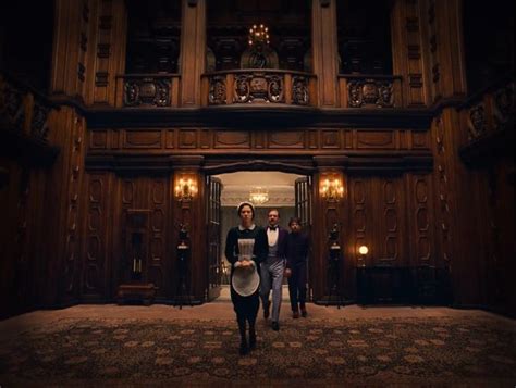 Two People Are Walking In Front Of An Ornate Building With Wood Paneled