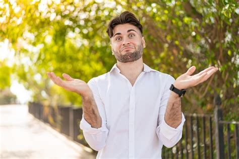 Hombre Guapo Joven Al Aire Libre Haciendo Gesto De Dudas Foto Premium