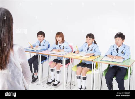 Four Elementary School Students In School Uniforms Seated At Desk