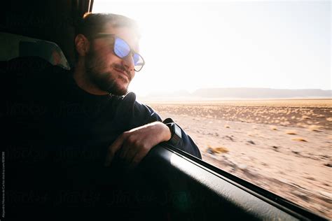 Young Man Looking Out The Passenger´s Window Of A Vehicle During A Road Trip By Stocksy