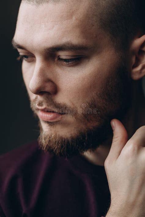 Close Up Portrait Of A Serious Young Man Looking Down On Gray