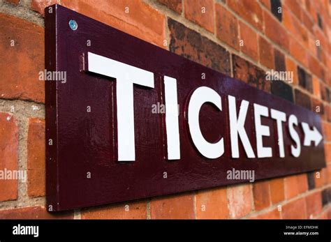 Close Up Of A Large Tickets Sign With Arrow Mounted On A Brick Wall