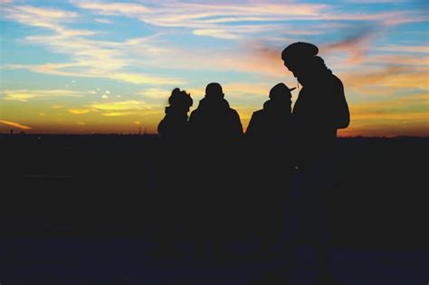 Siluetas De Personas Contra El Cielo Durante La Puesta De Sol Foto