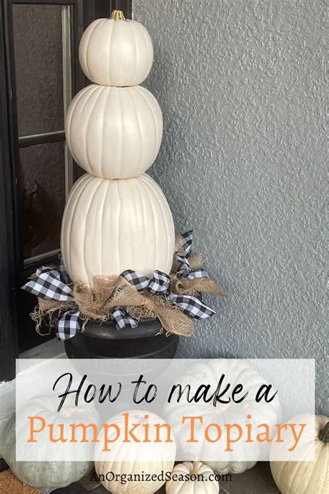 A Pumpkin Topiary Made With Three White Pumpkins Stacked On A Black Urn