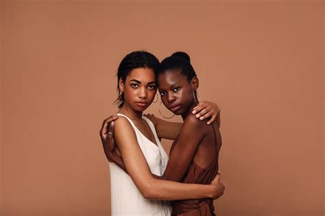 Premium Photo Portrait Of Lesbian Couple Embracing Against Brown