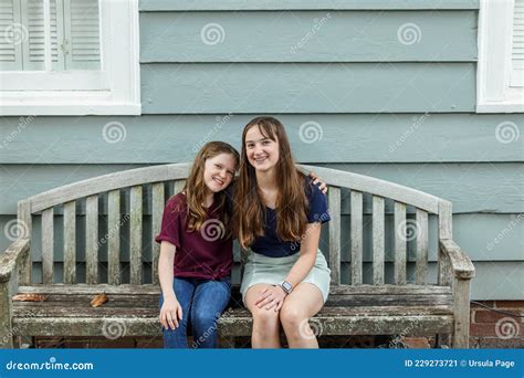 Two Sisters Embracing And Hugging On A Bench Outside Stock Image