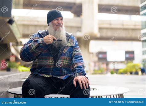 Mature Handsome Hipster Man Combing Beard In The City Streets Outdoors