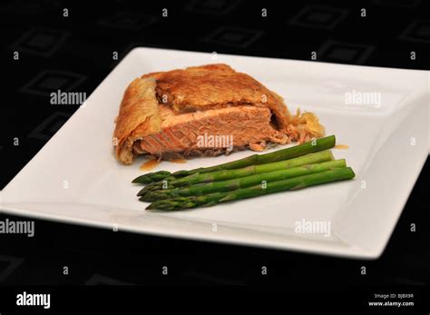 Salmon en croute with Green Asparagus on white serving plate on black ...