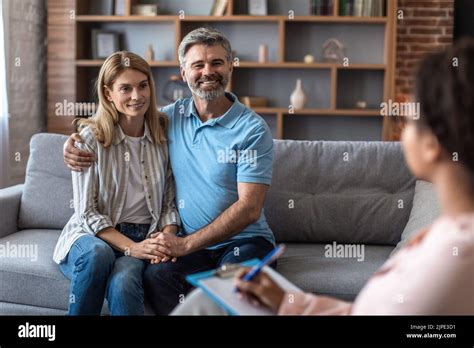Smiling Mature Caucasian Man And Lady Hugs At Meeting With Psychologist