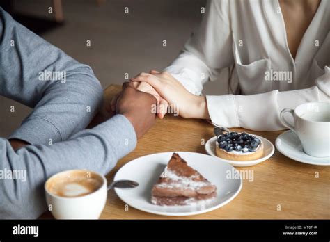 Interracial Couple Holding Hands Sitting At Cafe Table Closeup Stock