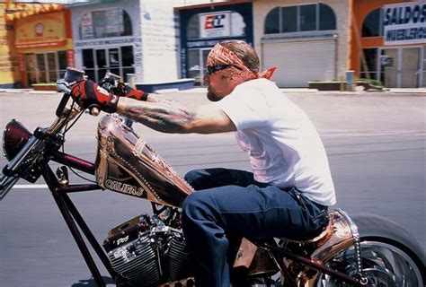 A Man Riding On The Back Of A Motorcycle Down A Street