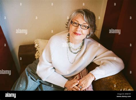 Interior Portrait Of 50 55 Year Old Woman Sitting On Couch Wearing