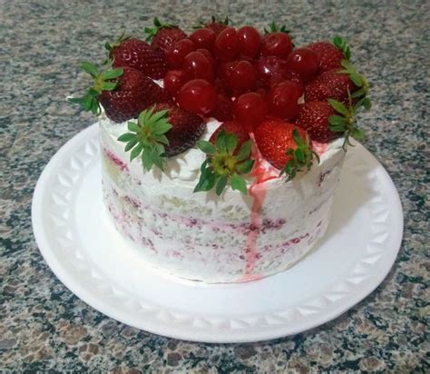 A Cake With Strawberries On Top Is Sitting On A White Plate And Sits On