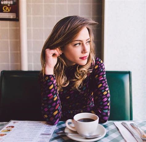 A Woman Sitting At A Table With A Cup Of Coffee In Front Of Her