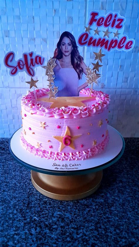 A Pink Cake With Gold Stars And A Photo On The Top That Says Feliz Cumple