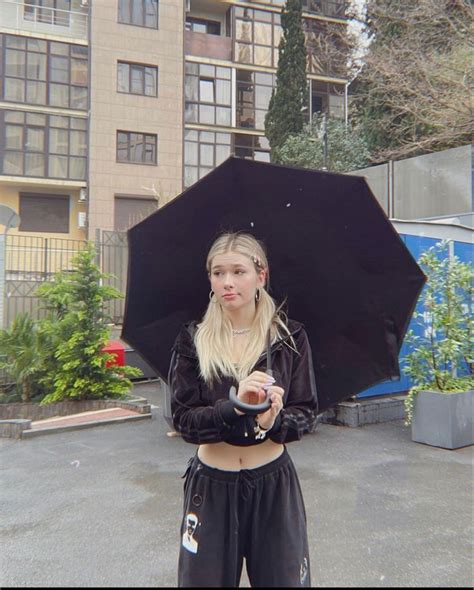 A Woman Holding An Umbrella In Front Of A Building