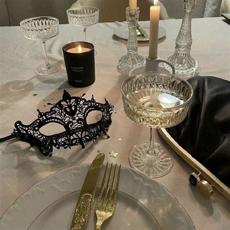 A White Table Topped With A Plate And Glasses Filled With Candles Next