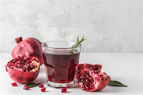 Glass Of Pomegranate Juice With Fresh Pomegranate Fruits And Rosemary On Marble Table Healthy