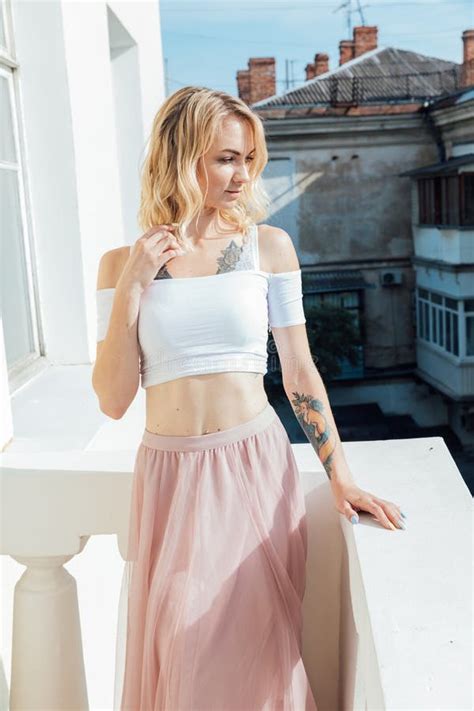 A Blonde Woman Standing On A Balcony Against A White Wall Stock Photo Image Of Clothing