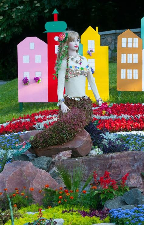 Macizo De Flores Con Las Flores Rojas En Un Fondo De Los Abetos Verdes