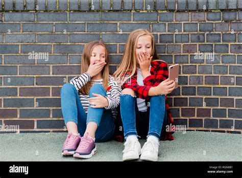 Portrait Two Girls Sitting Front Brick Wall Taking Selfie Smartphone Hi