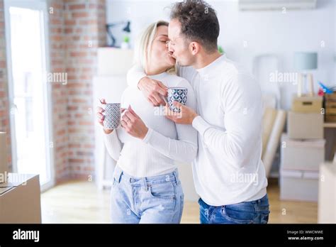 Young Beautiful Couple Standing Drinking Cup Of Coffee And Kissing At