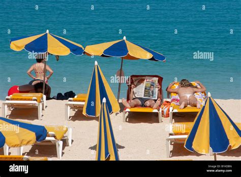 Man Reading Newspaper While His Partner Sunbathes Playa De Los