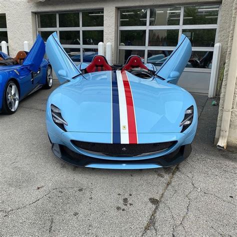 Two Blue Sports Cars Parked Next To Each Other In Front Of A Garage