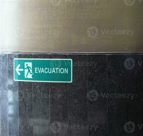 Selective fire exit sign on white ceiling. Green fire escape sign ...