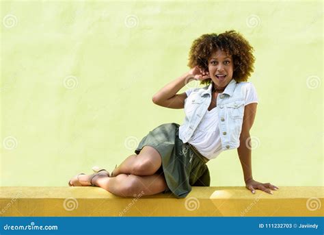 Young Black Woman Afro Hairstyle Sitting On An Urban Wall Stock Image