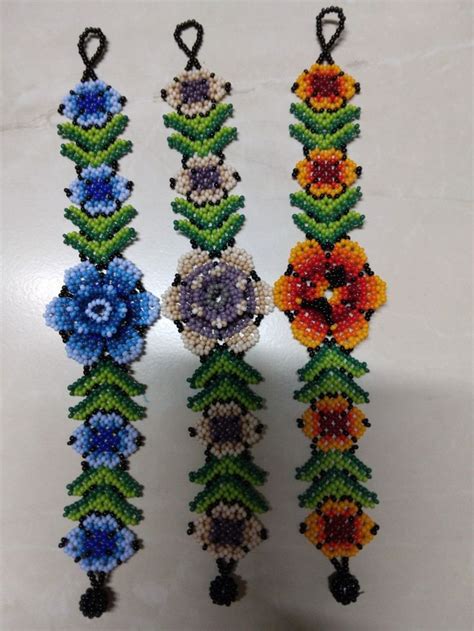 Four Beaded Bracelets With Flowers And Beads Hanging From Them On A