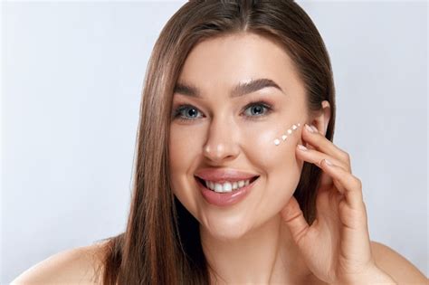 Mujer de belleza aplicar crema para la cara sosteniendo loción