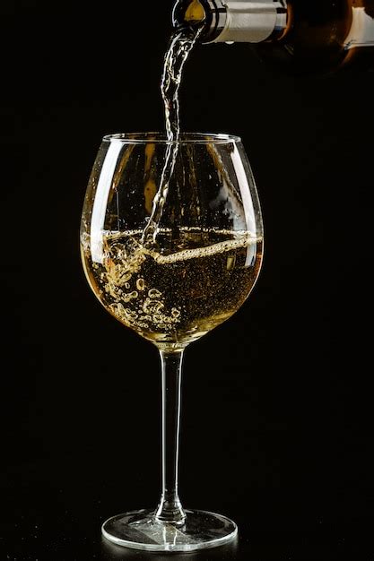 Premium Photo White Wine Being Poured In A Wine Glass On A Dark