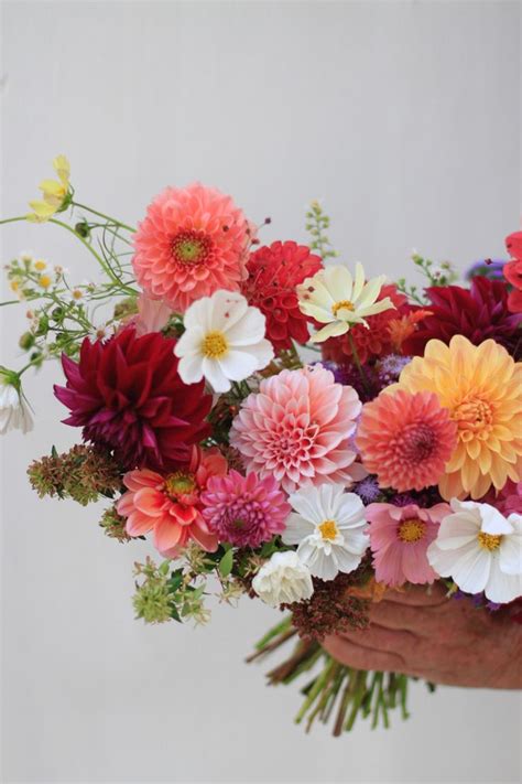 A Colorful Fall Bridal Bouquet Is Held For A Photograph Against A White