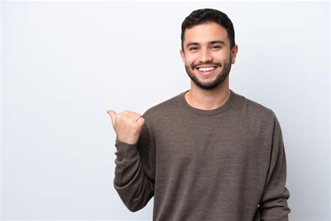 Joven brasileño aislado sobre fondo blanco apuntando hacia el lado para