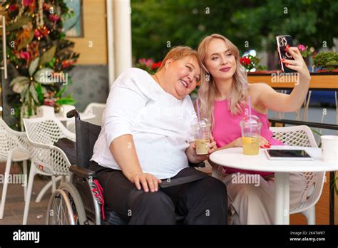 Portrait Of Mature Mother In Wheelchair And Her Daughter Making A