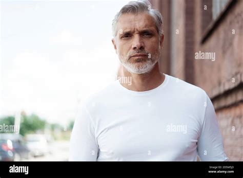 Portrait Of A Grey Haired Mature Handsome Man In Jeans And White T
