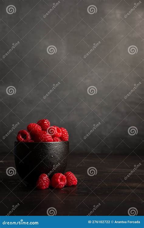 View Of Black Bowl With Red Raspberries On Dark Table With Three