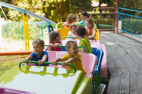 Los Niños Felices En Una Montaña Rusa En El Parque De Atracciones Foto