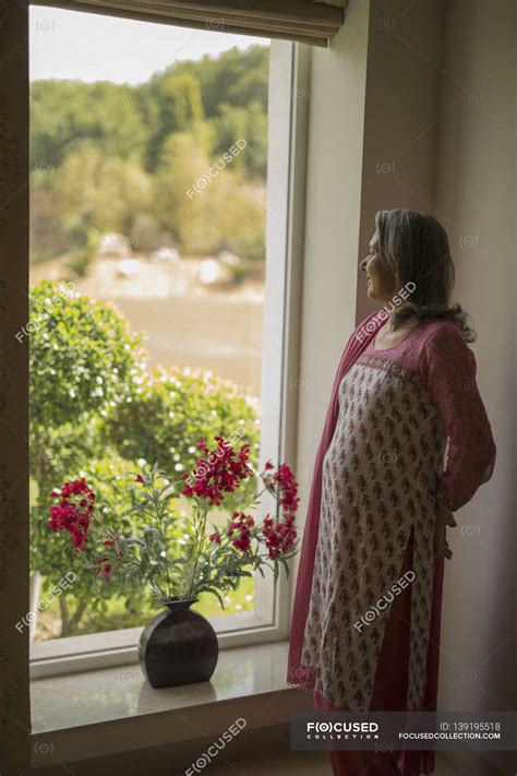 Mature Woman Looking Out Window Vase Indoor Stock Photo