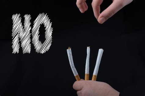 Premium Photo Cropped Hand Holding Cigarettes Against Black Background