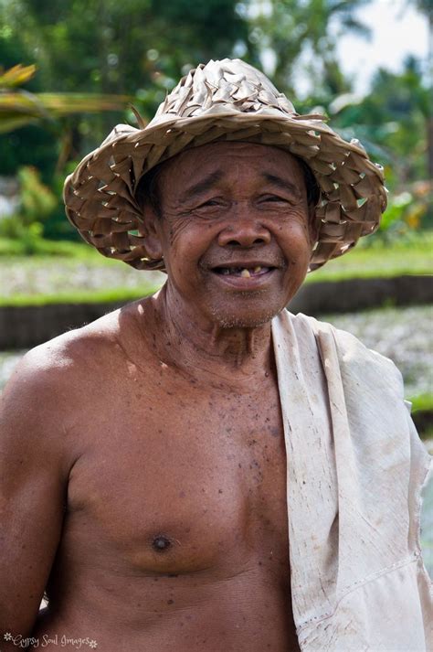 An Old Man With No Shirt Wearing A Straw Hat And Holding A Towel Over