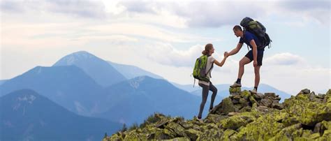 Junge touristen mit rucksäcken athletischer junge hilft dünnem mädchen